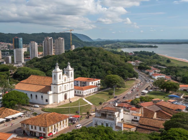 Vista aérea de Paranaguá, Paraná, com igreja histórica, litoral e prédios modernos ao fundo.