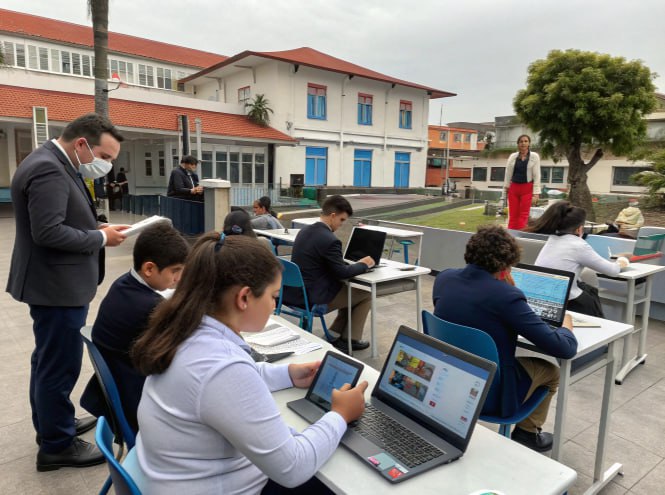 Alunos estudando em ambiente externo no Paraná com notebooks e tablets, acompanhados por professores.